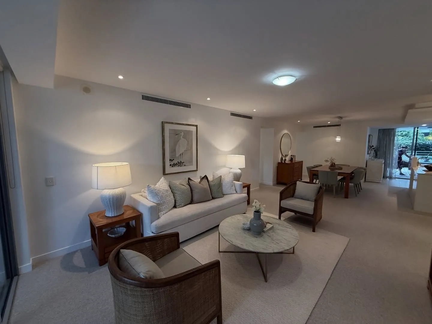 Apartment living room in New Farm with white walls, a white sofa, a round coffee table and framed art